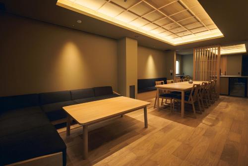 a room with a couch and tables and chairs at Apartment Hotel UCHIWA STAY Osaka NAMBA in Osaka