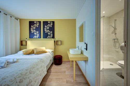 a bedroom with a bed and a sink and a bathroom at Hôtel Paul in Aix-en-Provence