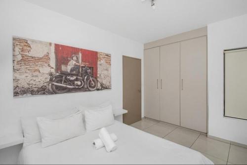 a bedroom with a white bed and a painting on the wall at Soho Junction fourways in Sandton