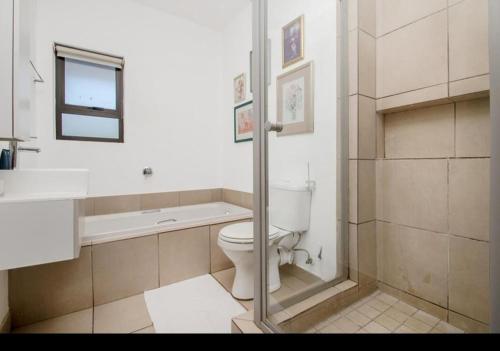 a bathroom with a toilet and a tub and a sink at Soho Junction fourways in Sandton