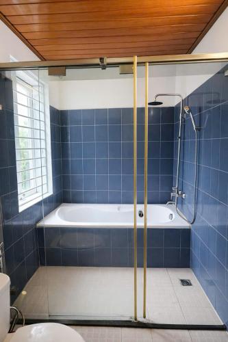 a blue tiled bathroom with a tub and a toilet at Davidduc Villa 30 Tay Ho in Hanoi