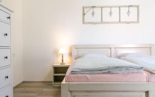 a bedroom with a bed and a dresser with a lamp at Chalupa Hlohovec in Hlohovec