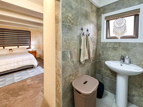 a bathroom with a sink and a shower and a bed at Ganstever Suiderstrand Western Cape in Suiderstrand
