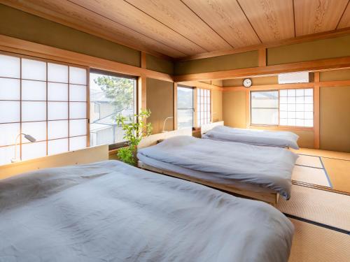 two beds in a room with two windows at Guesthouse NAMAZU in Anan