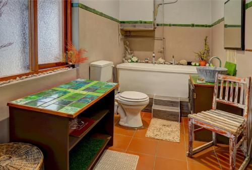 a bathroom with a toilet and a tub and a chair at Harbour House Mossel Bay - near sea & activities in Mossel Bay
