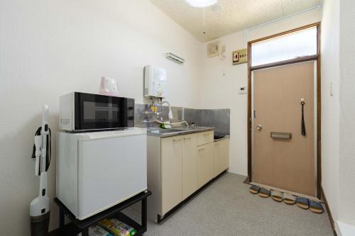 a kitchen with a refrigerator and a microwave at Kawagoe Good Place Apartment in Kawagoe