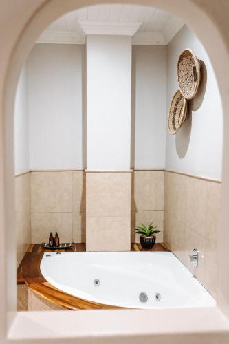 a large white bath tub in a room with an archway at Knysna Elephant Park Lodge in Plettenberg Bay