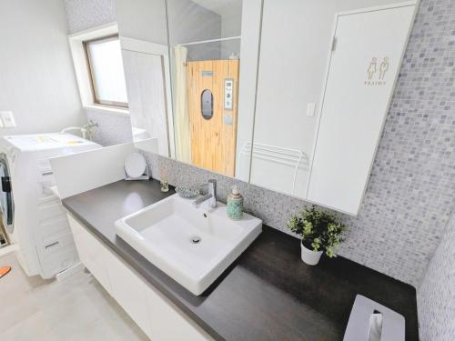 a bathroom with a white sink and a mirror at アンドスティ鴨川 in Kamogawa