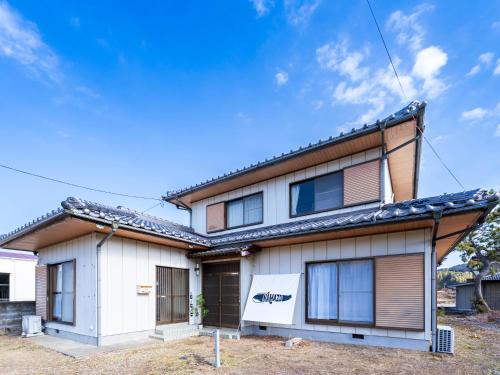 a house with a blue sky in the background at Guesthouse NAMAZU in Anan