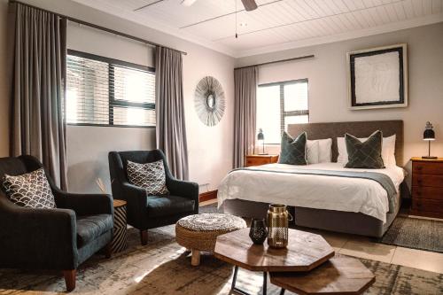 a bedroom with a bed and two chairs and a table at Knysna Elephant Park Lodge in Plettenberg Bay