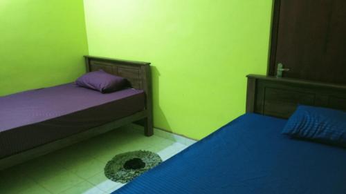 two beds in a room with green and purple at Pasindu Garden in Vavuniya