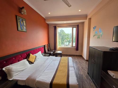 a bedroom with a large bed with a red wall at Hotel Ganges Park in Haridwār