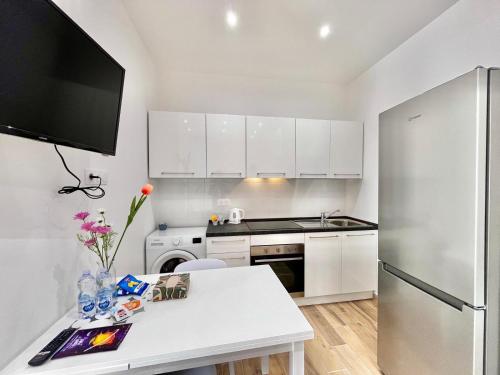 a white kitchen with a refrigerator and a table at Comfortable 1-Bedroom Central Menton in Menton