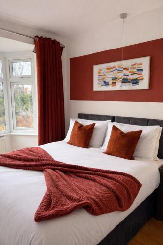 a bedroom with a large bed with red and white pillows at Parkfield House in Smethwick