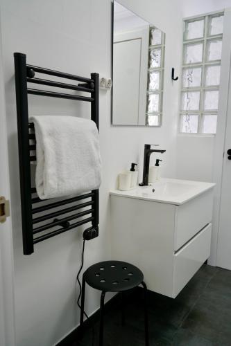 a white bathroom with a sink and a stool at Apartamentos Campus Arzúa in Arzúa