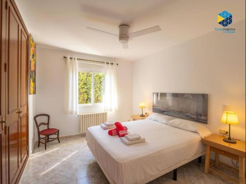 a bedroom with a white bed and a red chair at Can Moragues and Martorell in Badia Blava