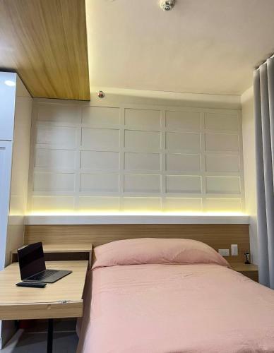 a bedroom with a bed and a laptop on a desk at Suite Talie Cebu Cozy Modern Stay with Pool & Netflix in Lapu Lapu City