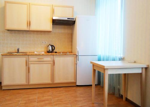 cocina con nevera blanca y mesa en Apart-Hotel Kurkino, en Moscú