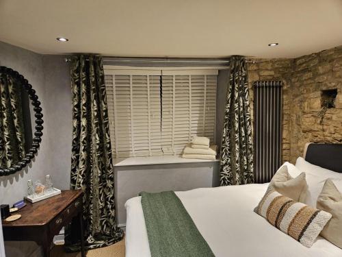 a bedroom with a bed and a window with a bath tub at Cotswold Cottage Guest House in Stow on the Wold