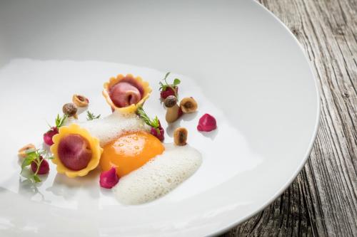 a white plate with food on a wooden table at Minglers Sportalm - Das Gourmet- und Genießerhotel in Kirchberg in Tirol