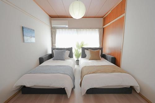 two beds in a small room with a window at INA HOUSE Higashi-Fuchu 101 in Fuchu