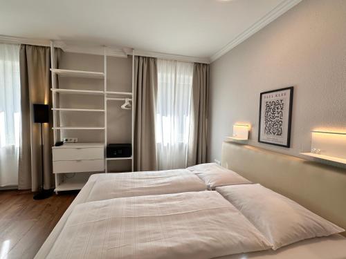 a bedroom with a large white bed and a shelf at Hotel Villa Solln - free parking in Munich