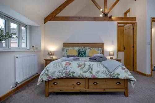 a bedroom with a large bed with a wooden headboard at Bamford Barn in Ottery Saint Mary