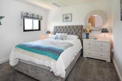 a bedroom with a bed and a mirror and a dresser at 2 Bed in Abererch oc-glwysf in Abererch