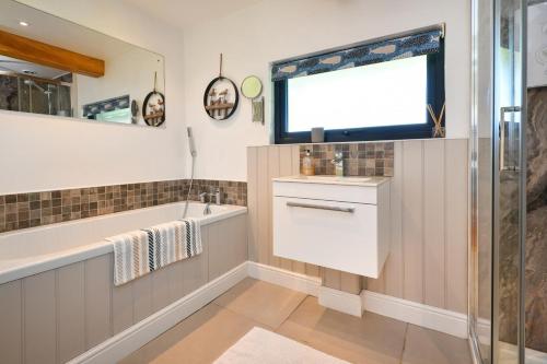 a bathroom with a sink and a tub and a window at 2 Bed in Abererch oc-glwysf in Abererch