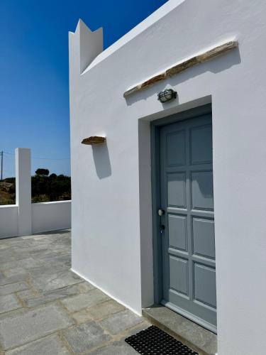 a blue door on the side of a white house at Iosub Houses & Studios - Beach House in Koumbara in Tzamaria