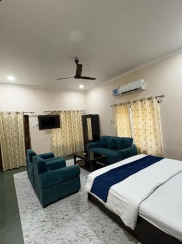 a bedroom with a bed and two chairs and a television at Hotel Indra Palace Jaunpur in Jaunpur