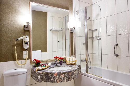 a bathroom with a sink and a shower and a toilet at Güneş Hotel Merter in Istanbul