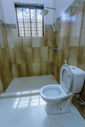 a bathroom with a toilet and a shower with a window at Dream Kilimanjaro Complex Hotel in Msaranga