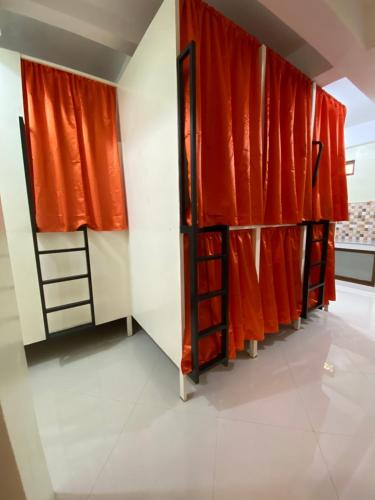 a room with orange curtains and a row of bunk beds at B2 Capsule Sleep Pods in Guiuan