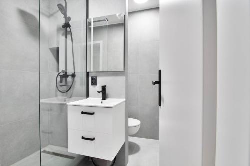 a white bathroom with a sink and a shower at Moskovska with Public Parking in Banská Bystrica