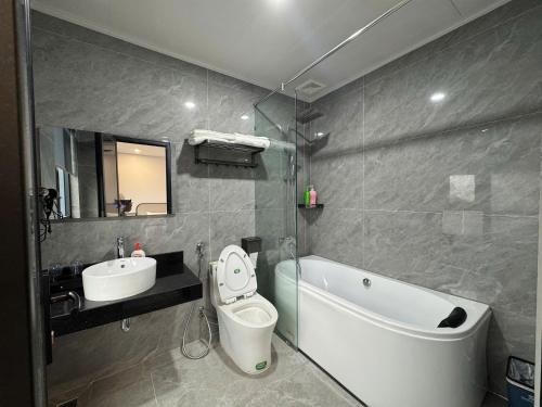 a bathroom with a sink and a toilet and a bath tub at Lâm Luxury Hotel Lào Cai in Chơ Mơi