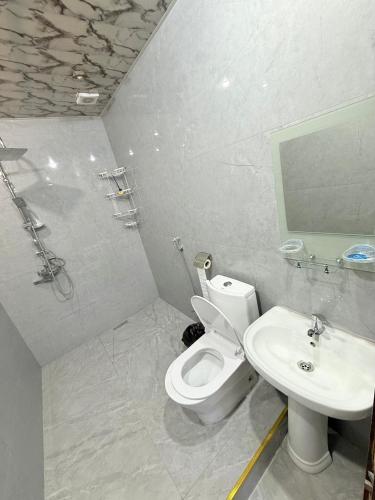a white bathroom with a toilet and a sink at Elit Hostel Qabala in Gabala