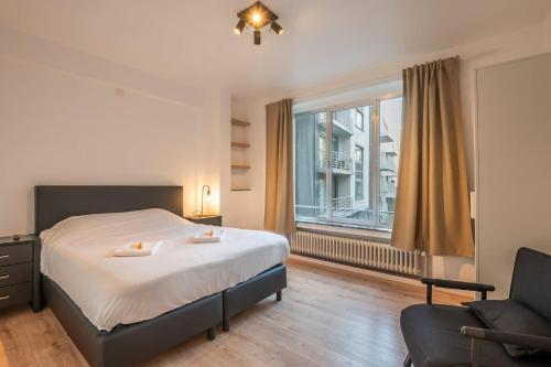 a bedroom with a bed and a chair and a window at Appartement Montfleuri in Ostend