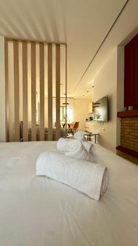 a large white bed with white towels on it at By The River Stay in Florina