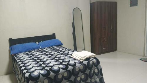 a bedroom with a bed with blue sheets and a dresser at RnR Suites in Dagupan