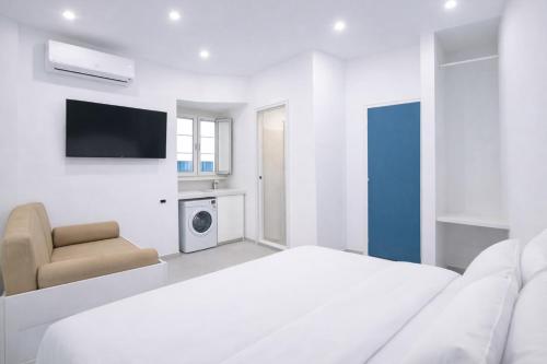 a white bedroom with a bed and a chair at Casa Schiattarella Napoli in Naples