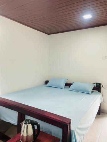 a white bed with blue pillows in a room at Hobbit in Midigama East