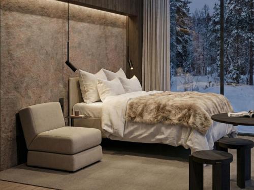 a bedroom with a bed and a chair and a window at Halo Igloos Resort in Rovaniemi