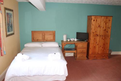 a bedroom with two beds and a desk with a television at The Menai Hotel and Bar in Bangor
