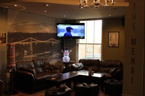 a living room with leather furniture and a flat screen tv at The Menai Hotel and Bar in Bangor