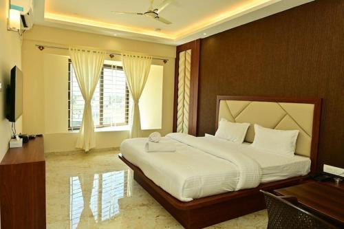 a bedroom with a large bed with a desk and a window at Siddarth Residency in Channarāyapatna