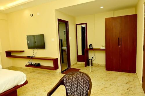 a bedroom with a bed and a television and a chair at Siddarth Residency in Channarāyapatna