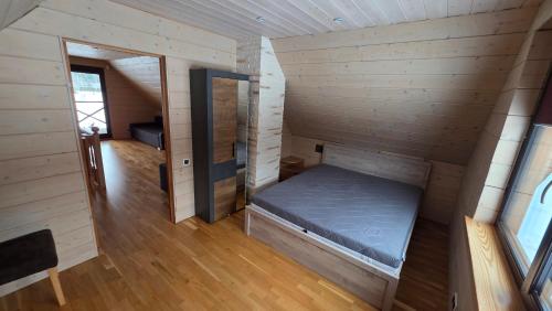 a small bed in a room with wooden walls at Ramaus poilsio sodyba in Petruniškis