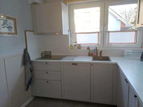 a kitchen with white cabinets and a sink and a window at Biały Domek in Stegna