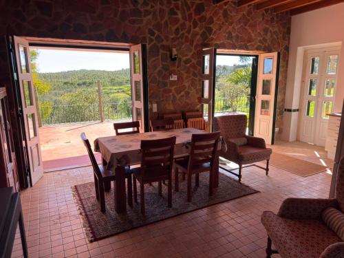 a dining room with a table and chairs and a balcony at Colonial Farmhouse with Cottage - Lugar Minas da Caveira in Grândola